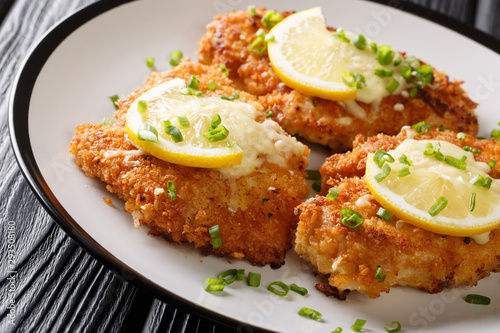 Serving romano chicken cutlet fried breaded with lemon and green onion closeup on a plate. horizontal