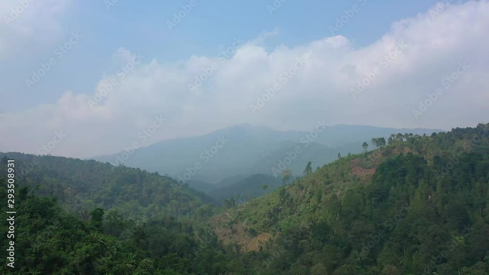 Aerial view of drone in tropical rain forest with mountain, valley and clouds. backward pullback flying motion Aerial view of drone in tropical rain forest with mountain, valley and clouds. backward pullback flying motion