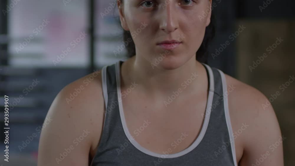 Tilt up shot of young woman wrapping hands for boxing and then looking at camera before training in gym Tilt up shot of young woman wrapping hands for boxing and then looking at camera before training in gym