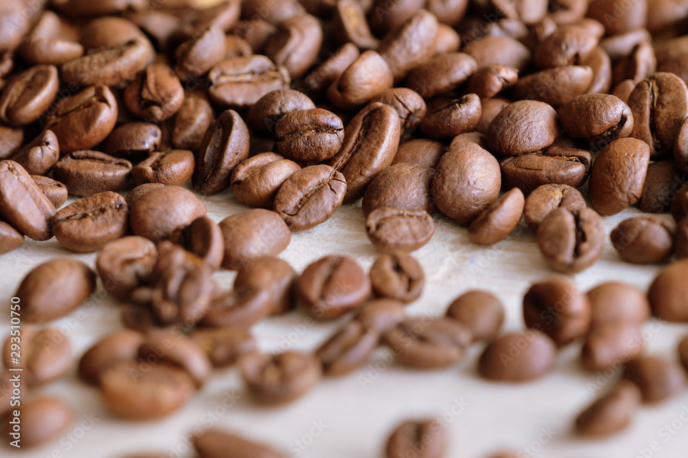 Roasted coffee beans scattered on a wooden surface close up Roasted coffee beans scattered on a wooden surface close up