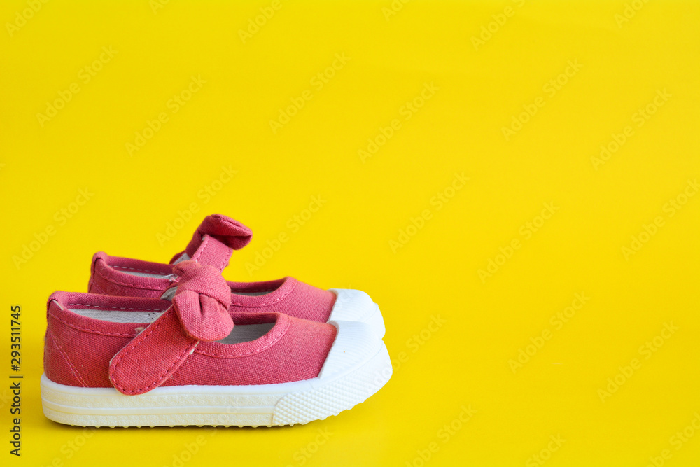 Pink shoes for children isolated on a yellow background. Pink shoes for children isolated on a yellow background.
