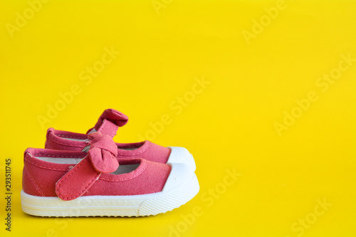 Pink shoes for children isolated on a yellow background.