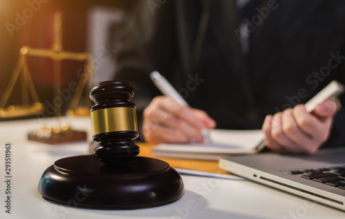 Justice and law concept.Male judge in a courtroom the gavel, working with digital tablet computer on wood table in sun light.