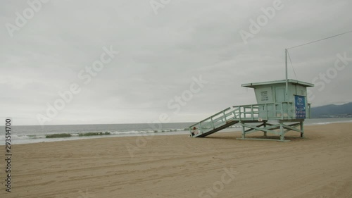 Caucasian female sits near lifeguard tower on Santa Monica beach in Los Angeles, California, USA