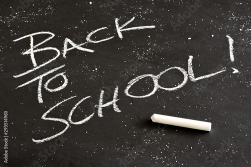 Back to school written on a blackboard with chalk dust and a stick of chalk.