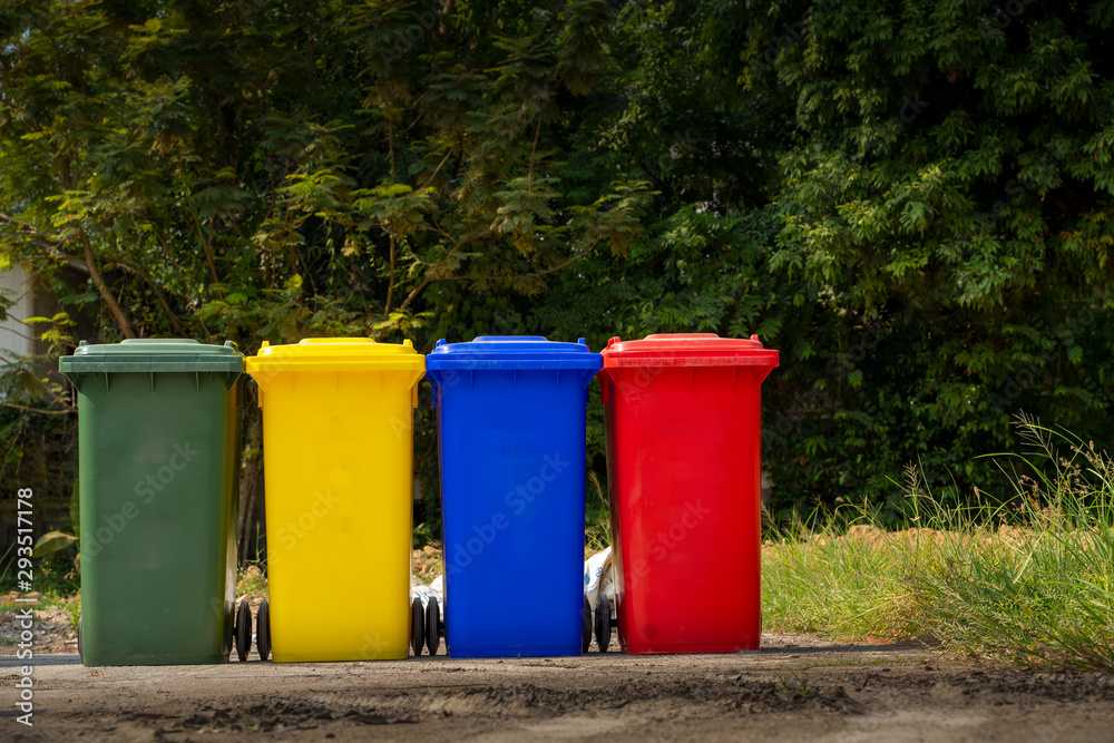 Trash bin standing on industrial site,Trash bin color red,blue,yellow with green and black paint on wheels. Trash bin standing on industrial site,Trash bin color red,blue,yellow with green and black paint on wheels.