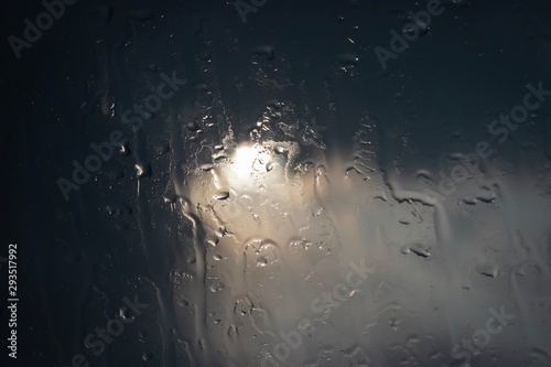 Abstract of water drops on glass window, dark tone, selective focus..