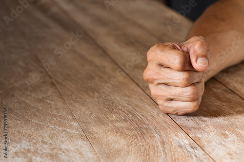 Man's clenched fist on vintage wooden table