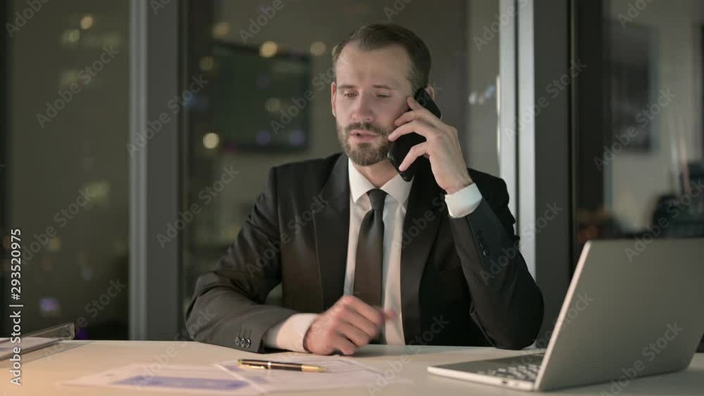 Ambitious Businessman talking on Cellphone in Office at Night Ambitious Businessman talking on Cellphone in Office at Night