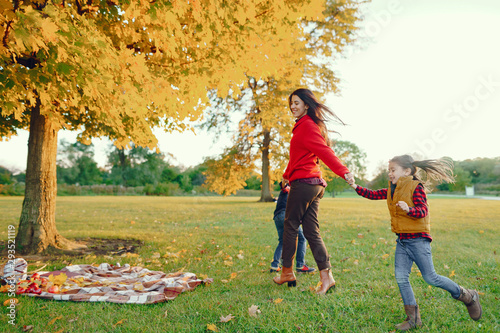 Fototapeta Naklejka Na Ścianę i Meble -  Cute family in a autumn park. Happy mother with little kids. Family playing on yellow leaves. Golden autumn.