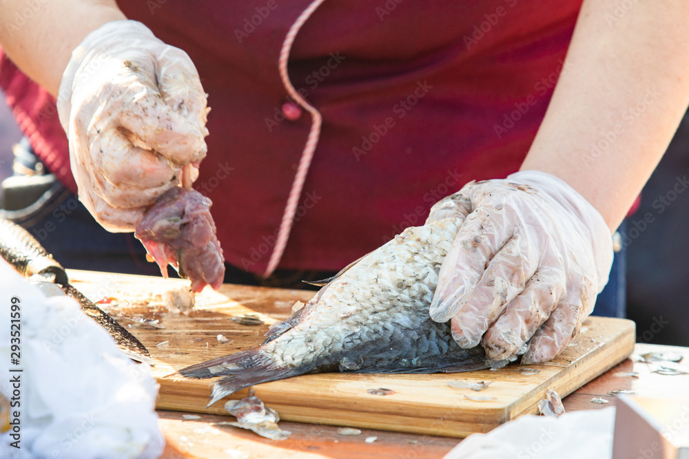 On the table, clean the fish from the scales and remove the entrails. Peeling and fillet of fresh fish that use a knife to clean the fish. Seafood cooking.