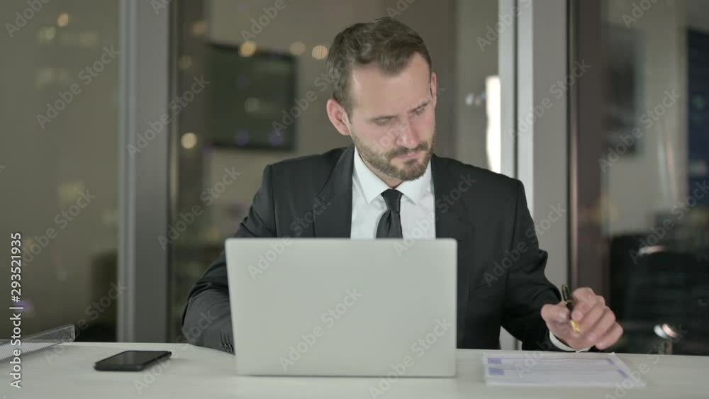 Young Businessman working on Laptop and Document at Night Young Businessman working on Laptop and Document at Night