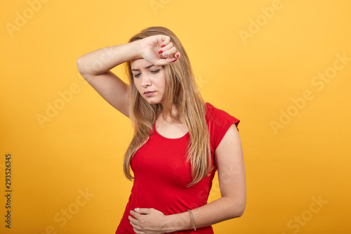 young blonde girl in red t-shirt over isolated orange background shows emotions