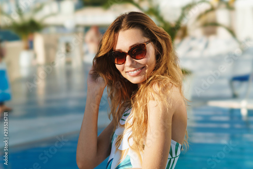 Image of a positive pretty young woman posing at the pool party outdoors.