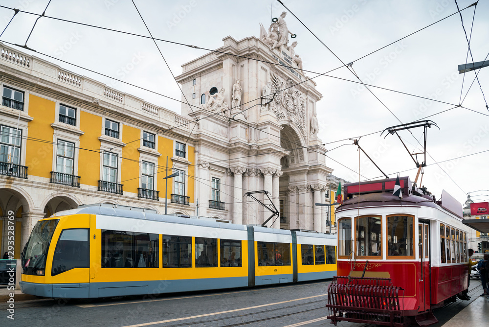 Old and modern trams collide in front of the Triumphal Arch in the Praça do Comércio, Lisbon, Portugal