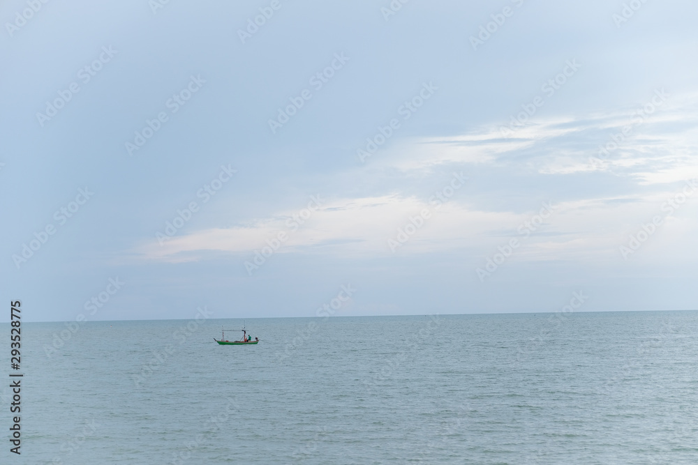 Small Thai Commercial fishing boat,look so far can see fisherman in the sea. Boat fishing trawler flooding with water waving on blue clouds sky background in Thailand.