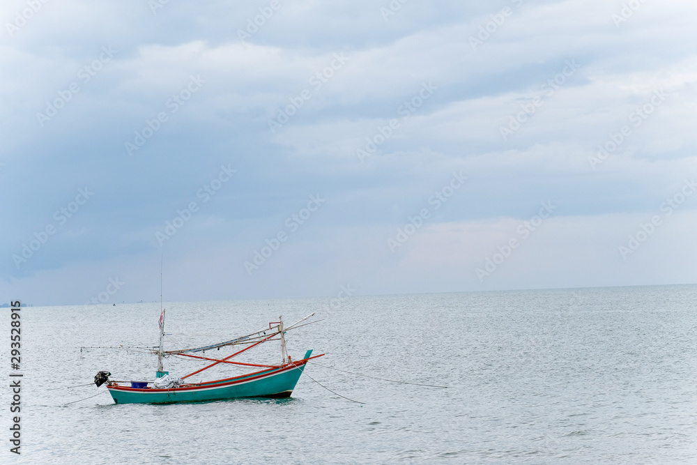 Close up small Thai Commercial fishing green boat and Seascape in the sea.the boad dock with anchor and rope on the sea,fishing trawler flooding with water waving with blue clouds sky in Thailand.