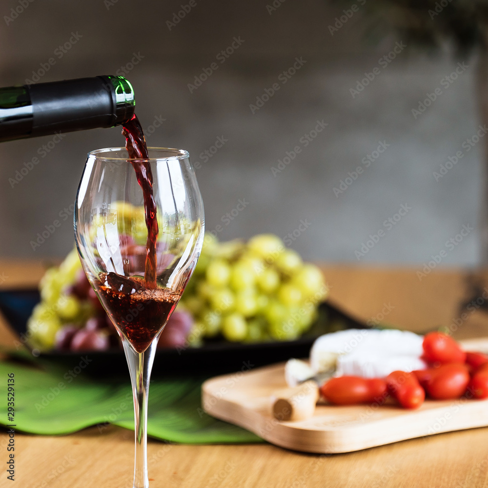 Obraz premium Waiter pouring red wine into wineglass. 