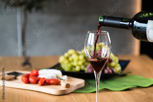 Waiter pouring red wine into wineglass. 