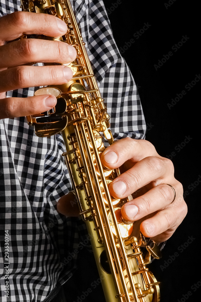 Naklejka premium soprano saxophone in hands on a black background