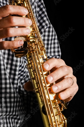 soprano saxophone in hands on a black background