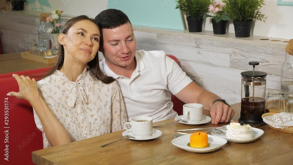 lovely young couple drinks fresh tea during date sitting at wooden table in cozy confectionery shop lovely young couple drinks fresh tea during date sitting at wooden table in cozy confectionery shop