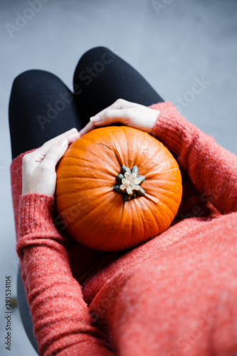 A woman is holding a ripe pumpkin