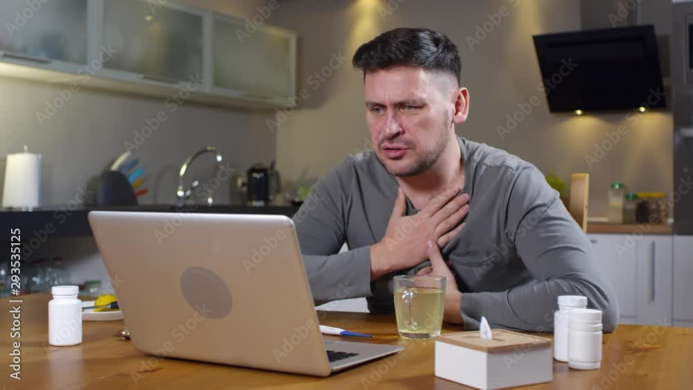 Medium shot of man with cold sitting at kitchen table and describing his symptoms to doctor on video call Medium shot of man with cold sitting at kitchen table and describing his symptoms to doctor on video call
