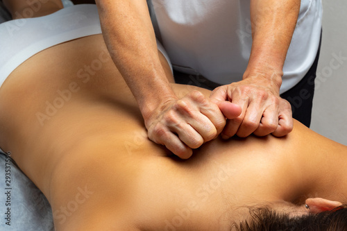 Hands activating muscles on woman s back.
