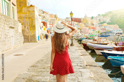 Holidays in Italy. Back view of beautiful girl in stunning colorful harbor of Procida, Italian Capital of Culture 2022. photo