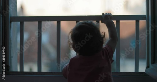 little child standing by the window looks into the yard. Shot on Canon 1DX mark2 4K camera photo