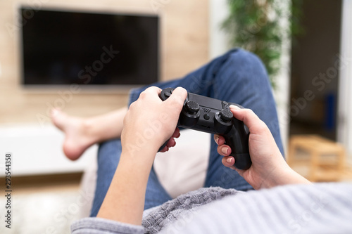 POV Woman lying on the coach in front of TV and holding in hands wireless game controller. Game addiction concept.