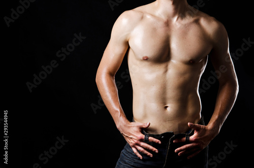 Slim muscular male torso at black background
