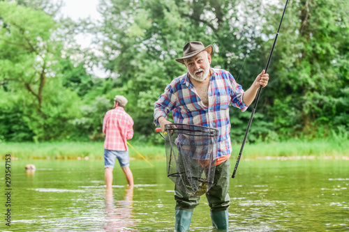 fishing time. family bonding. summer weekend. two fishermen with fishing rods, selective focus. retired mature man fisher. hobby and sport activity. father and son fishing. male friendship