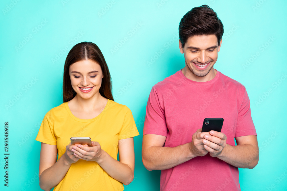 Portrait of his he her she nice attractive charming cute cheerful cheery focused couple using device gadget chatting online isolated over bright vivid shine vibrant green turquoise background