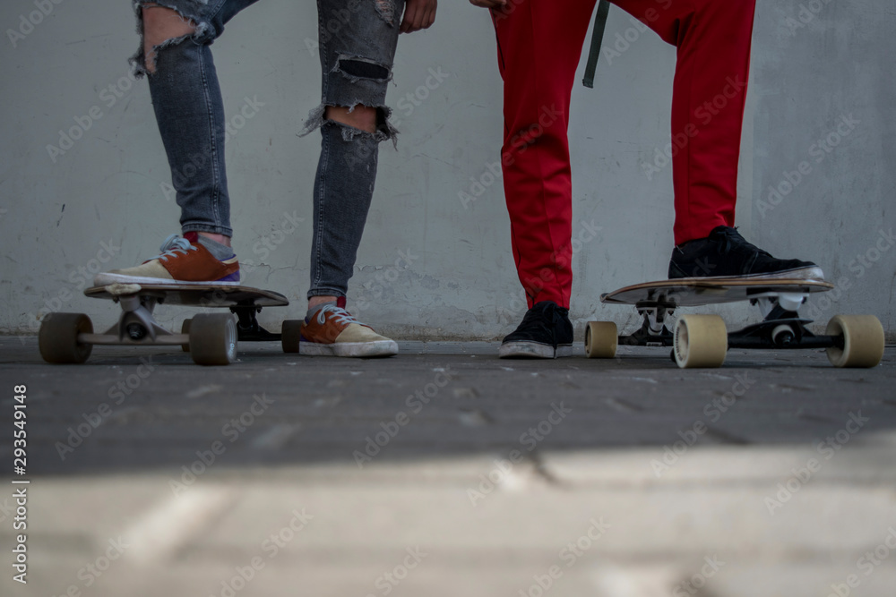 Two male skaters standing side by side with their skateboards on the ground low angle view Two male skaters standing side by side with their skateboards on the ground low angle view