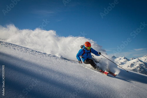 Ski instructor going down a ski slope with speed, well equipped and blue sky photo