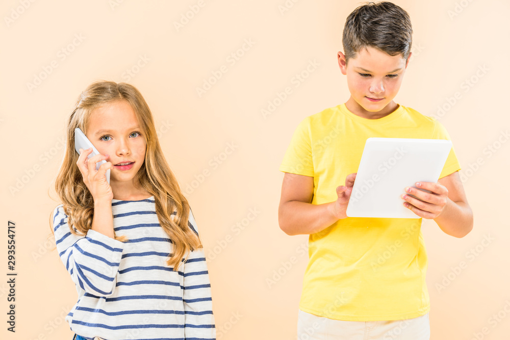 two kids using smartphone and digital tablet isolated on pink two kids using smartphone and digital tablet isolated on pink