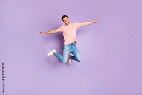 Full length photo of amazing guy jumping high pretending airplane flight spread hands wear casual outfit isolated on purple color background