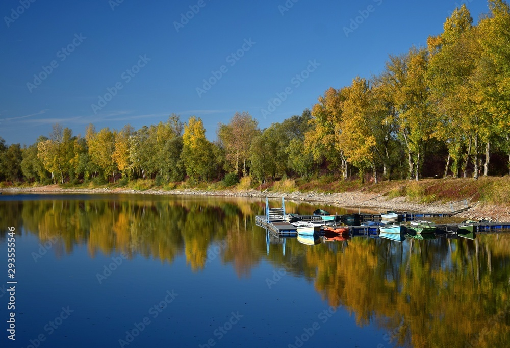 Autumn landscape with a lake, a boat bridge and some boats. - obrazy, fototapety, plakaty 