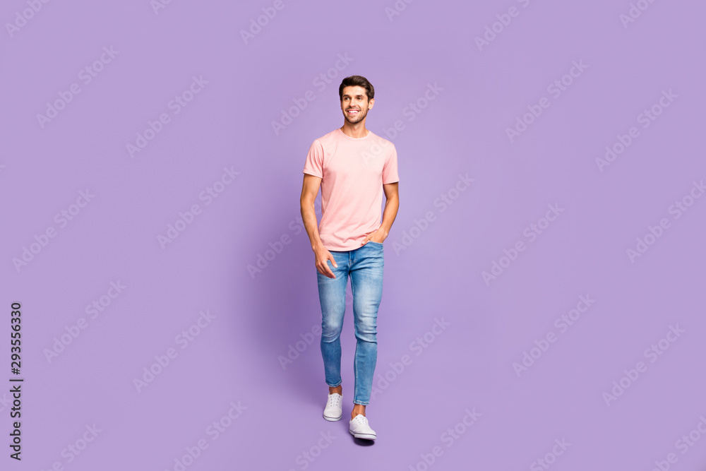 Full length body size view of his he nice attractive cheerful cheery content guy wearing pink tshirt strolling walking isolated on violet purple lilac pastel color background Full length body size view of his he nice attractive cheerful cheery content guy wearing pink tshirt strolling walking isolated on violet purple lilac pastel color background