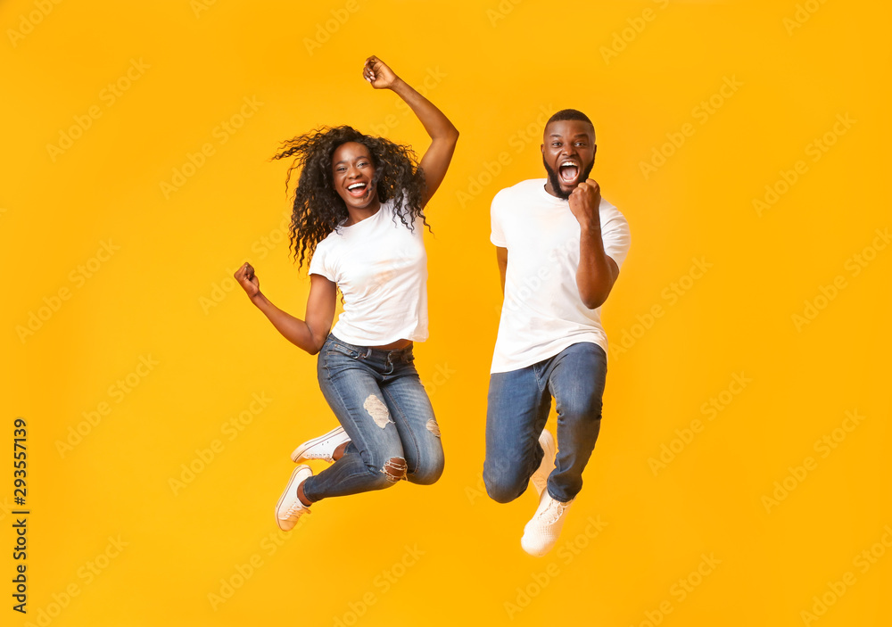 Joyful black couple jumping up and down - obrazy, fototapety, plakaty 