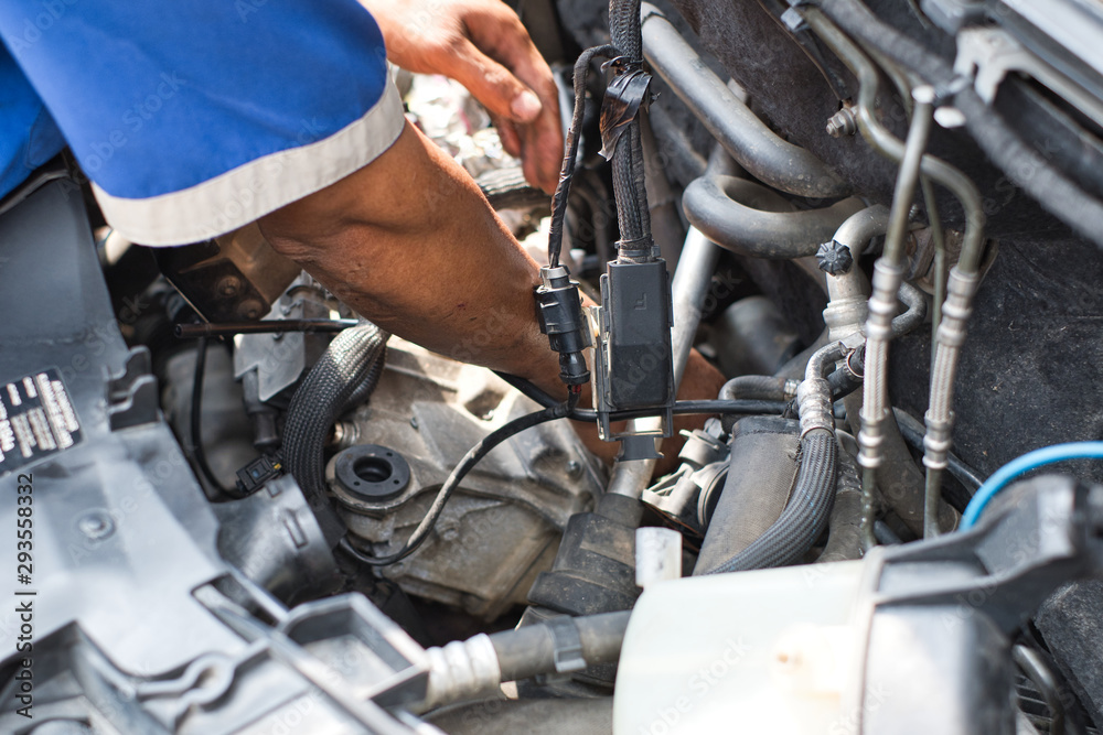 Close up of mechanic arm and hand fixing inside car engine room front hood open. Close up of mechanic arm and hand fixing inside car engine room front hood open.