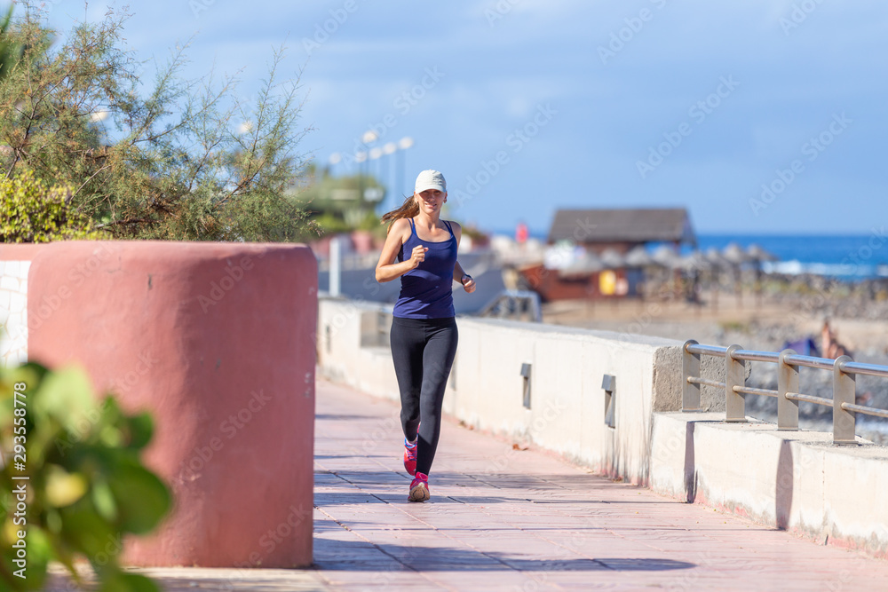 Young smiling girl jogging on the embankment in the morning Young smiling girl jogging on the embankment in the morning