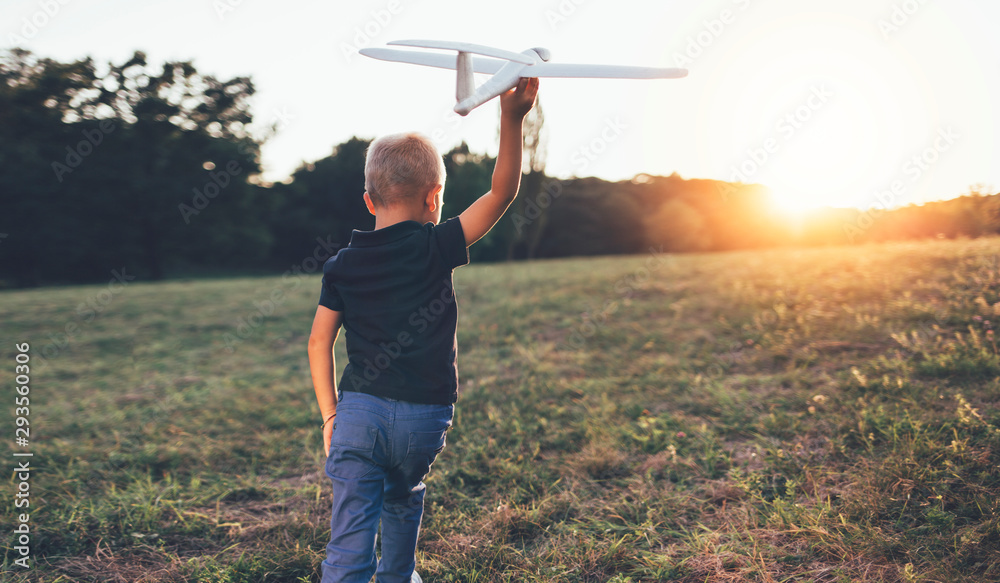 Rear view of boy with glider airplane model Rear view of boy with glider airplane model