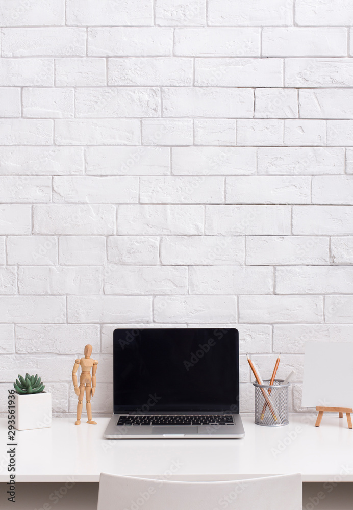 Laptop with blank screen in front of bricks wall in stylish office Laptop with blank screen in front of bricks wall in stylish office