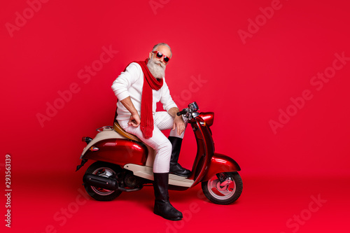 Fancy grandfather santa man posing sitting on vintage moped wear jumper and trousers isolated red background