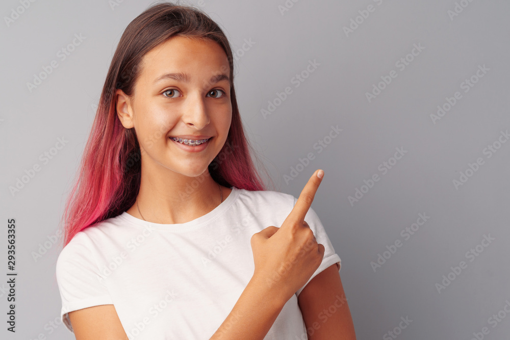 Smiling casual teen girlpointing finger at copy space. Smiling casual teen girlpointing finger at copy space.