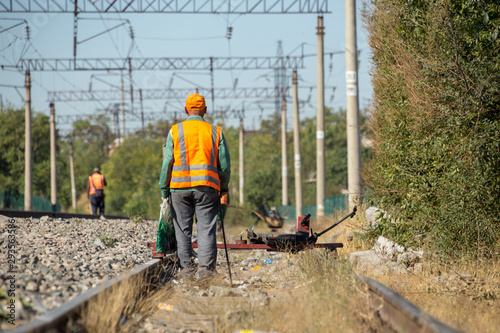workers check for broken old reinforced concrete sleepers to replace them with new ones on the railway using equipment © donikz