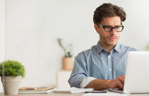 Obraz na plátně Concentrated Millennial Guy Working On Laptop At Work